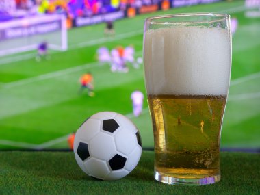 Bardak bira ve tv, futbol maçı arka planda