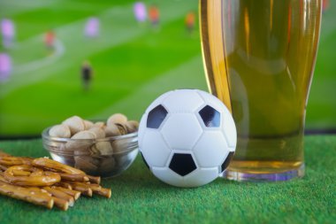 Bardak bira ve tv, futbol maçı arka planda