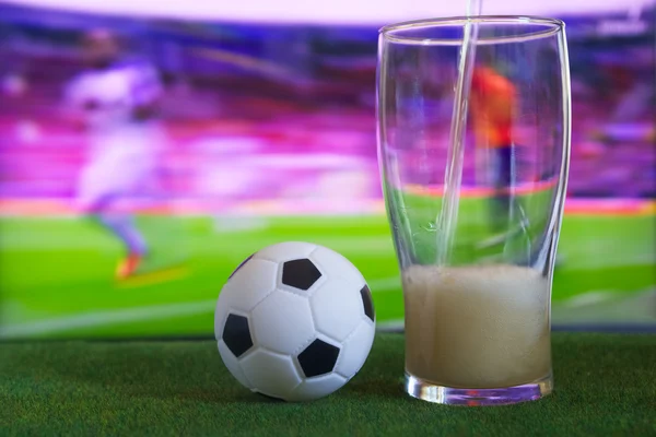 Vaso de cerveza y tv, partido de fútbol en el fondo — Foto de Stock