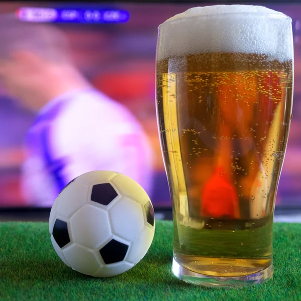 Copo de cerveja e tv, jogo de futebol em segundo plano — Fotografia de Stock