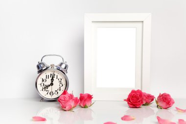 Boş beyaz bir çerçeve, pembe Gül ve çalar saat. Yukarı alay.