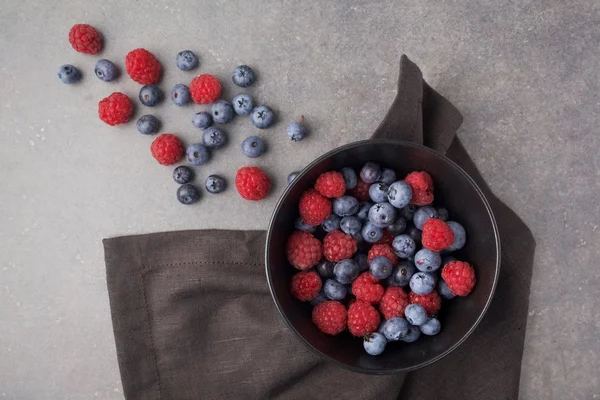 Bleuets et framboises dans un bol sur fond gris rouillé. Vue du dessus — Photo