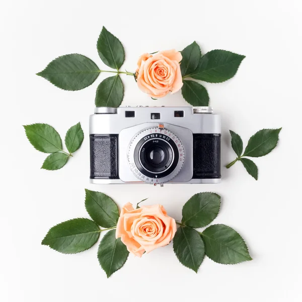 Vintage Fotokamera, orangefarbene Rosen und grüne Blätter, Draufsicht. flache Lage — Stockfoto