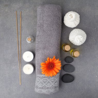 Gri bir yüzey üzerinde havlu, mum, masaj topları ve gerbera çiçekleri ile Spa hala hayat. Düz yatıyordu. Üstte görüntü