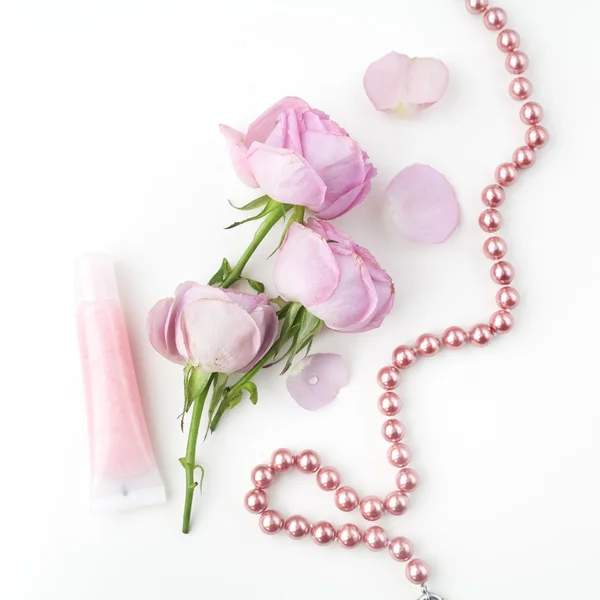 Roze rozen en parel ketting op witte achtergrond. Bovenaanzicht. — Stockfoto