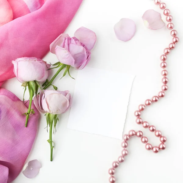 Pink roses and pearl necklace on white background. Top view. — Stock Photo, Image
