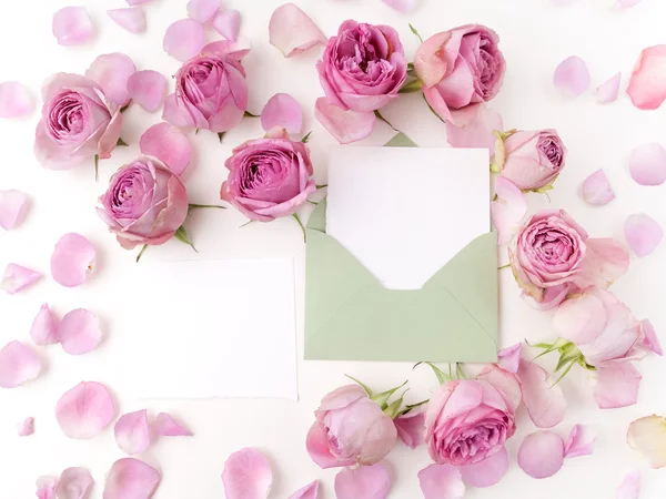 Envoltório de papel com cartão branco e rosas cor-de-rosa. Deitado plano, vista superior — Fotografia de Stock