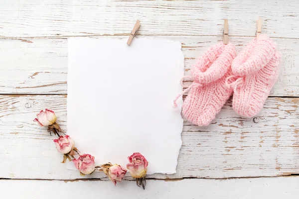 Chaussons roses pour bébés. Petite chaussette fille et carte blanche sur fond bois blanc — Photo