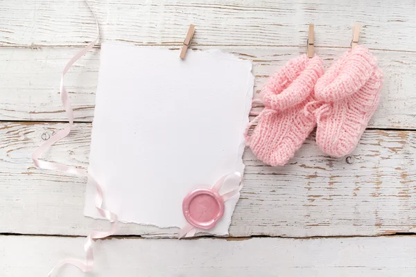 Rosa babys botines. Calcetín y tarjeta en blanco para niñas pequeñas con sello de cera sobre fondo de madera blanco —  Fotos de Stock
