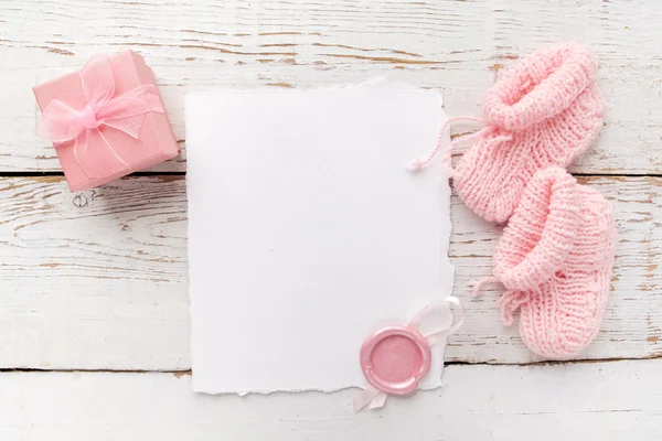 Baby Girl ubrania, pusta karta z woskiem pieczęć i małe obecne pudełko na białym tle drewnianym. Płaski lay. Widok owerhad — Zdjęcie stockowe