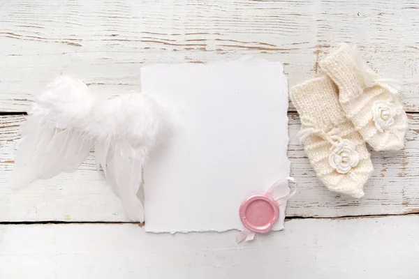 新生児またはバプテスマのグリーティングカード 白い木製の背景に女の赤ちゃんの手袋と天使の翼を持つブランク — ストック写真