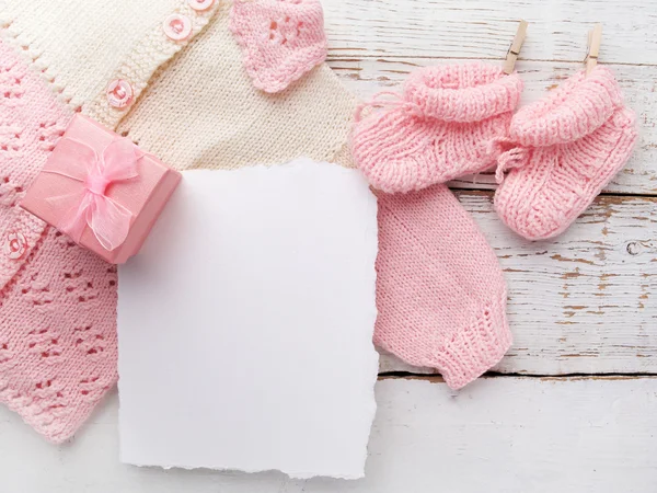 Ropa de niña con tarjeta en blanco sobre fondo de madera blanca. Acostado. Owerhad vista — Foto de Stock