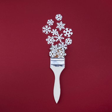 Kırmızı arka planda kar taneleri olan boya fırçası. Düz yatış, üst görünüm.