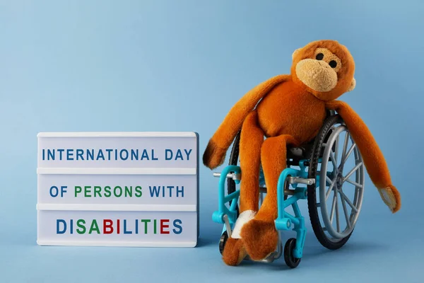 International day of persons with disabilities. Wheelchair wirh toy on blue background. — Stock Photo, Image