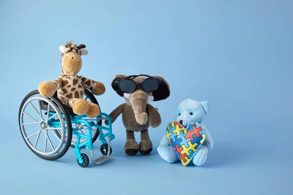 International day of persons with disabilities. Wheelchair with toys sign of different disabilities on blue background. — Stock Photo, Image