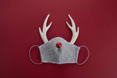 Yüz maskeli geyik boynuzları ve kırmızı top. Salgın Noel konsepti. Düz yatıyordu.