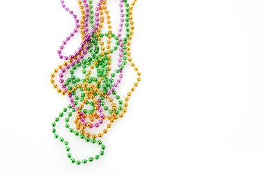 Beyaz arkaplanda üç renk Merdi Gras boncuğu var.