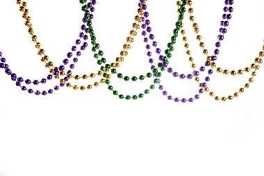 Beyaz arkaplanda üç renk Merdi Gras boncuğu var.