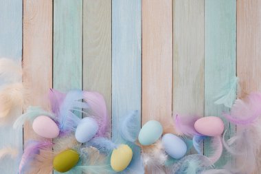 Mutlu Paskalyalar. Renkli Paskalya yumurtaları ve ahşap arka planda tüyleri olan çerçeve. Düz yatıyordu.