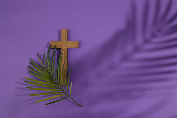 Palm sunday background. Cross and palm on purple background.