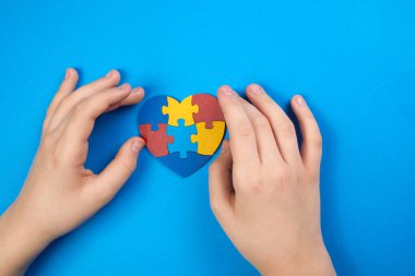 World Autism Awareness day, mental health care concept with puzzle or jigsaw pattern on heart with childs hands clipart