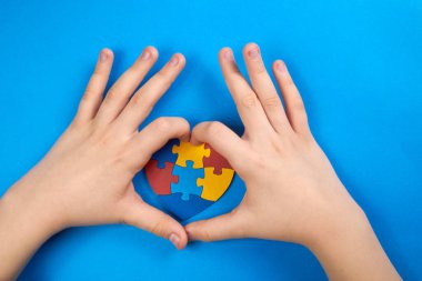 Dünya Otizm Farkındalık Günü, çocuk eli ile kalpte yapboz ya da yapboz desenli akıl sağlığı konsepti