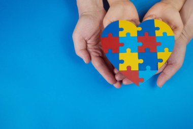 World Autism Awareness day, mental health care concept with puzzle or jigsaw pattern on heart with child and adult hands clipart