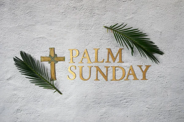 Palm sunday background. Cross and palm on grey background. Flat lay