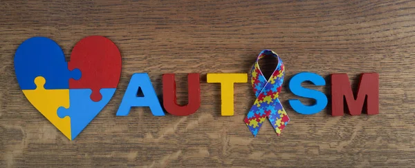 Conciencia del autismo. Cinta de conciencia autista, corazón y palabra autismo sobre fondo de madera. —  Fotos de Stock