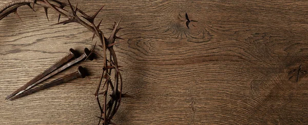 Crown of thorns with three nails on wooden background. Easter concept.