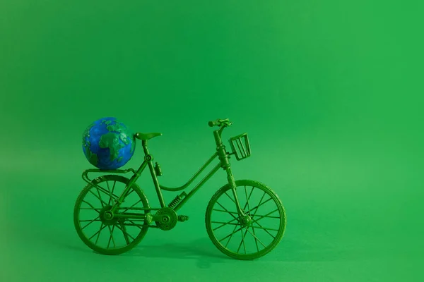 Giornata mondiale della bicicletta concetto. Bicicletta verde con globo su sfondo verde. 3 giugno. — Foto Stock