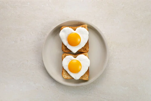 Hjärtformade ägg i rostade skivor rågbröd på keramiska tallriken. Älskar frukostdesign. Sund smörgås. Festlig lunch eller frukost. Äggdag. — Stockfoto