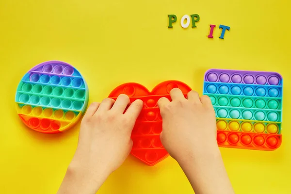 Mãos de criança brincando com pop colorido É brinquedo fidget. Colorido antistress brinquedo sensorial fidget empurrá-lo pop. — Fotografia de Stock