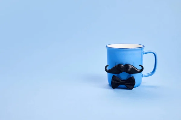 Kaffeetasse mit Schnurrbart und Fliege auf blauem Hintergrund. Happy Vathers Day Konzept — Stockfoto