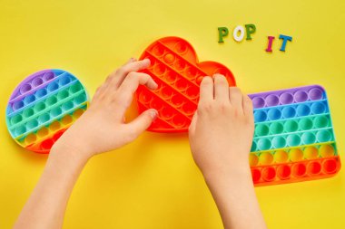 Çocuk elleri renkli şekerlemelerle oynuyordu. Renkli anti-stres oyuncağı. Kıpırda, kıpırda, kıpırda..