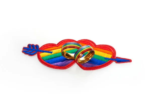 O amor ganha conceito com um coração multicolorido e anéis de casamento. Igualdade e proteção do amor — Fotografia de Stock