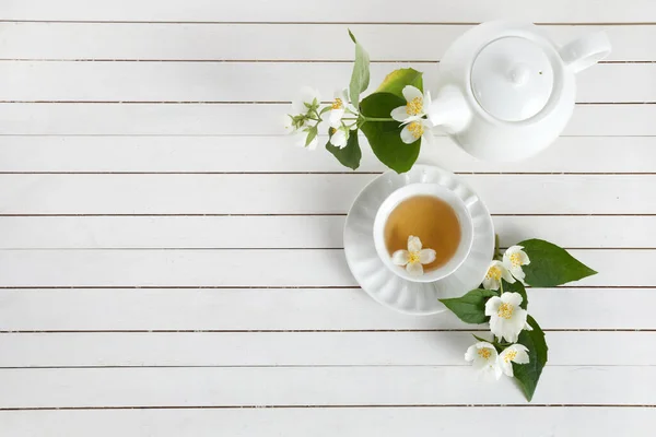 Yasemin çiçekleri ve çaydanlık beyaz ahşap arka planda. Yasemin çiçeğinden bitki çayı. Düz yatıyordu. — Stok fotoğraf