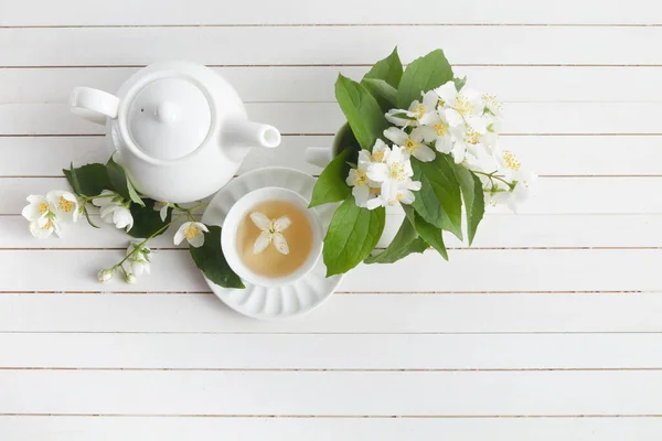 茉莉花和茶壶在白色木制背景。茉莉花草药茶。平躺在床上. — 图库照片