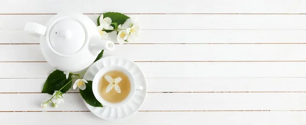Jasmín květiny a konvice na bílém dřevěném pozadí. Bylinkový čaj z jasmínového květu. Plocha. — Stock fotografie