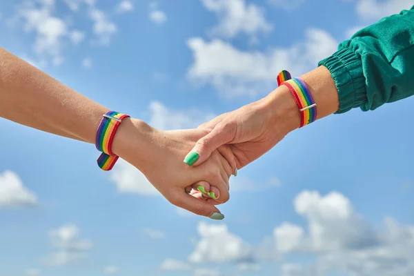 Duas mulheres caucasianas de mãos dadas com um pulso com padrão de arco-íris nos pulsos. — Fotografia de Stock
