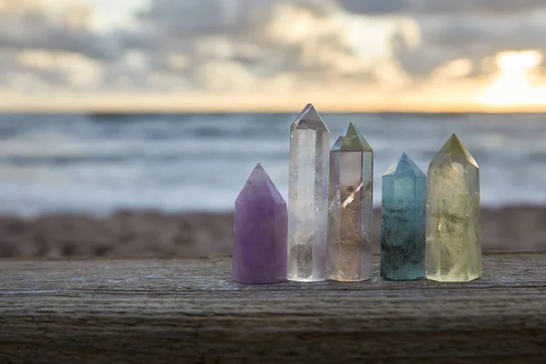 Heilende Reiki-Kristalle auf Holz mit Meer im Hintergrund bei Sonnenuntergang. Heilsteine am Meer. — Stockfoto
