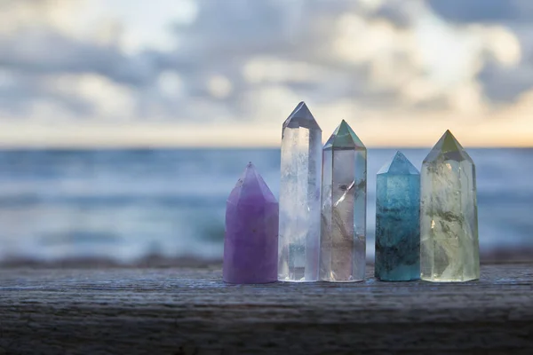 Heilende Reiki-Kristalle auf Holz mit Meer im Hintergrund bei Sonnenuntergang. Heilsteine am Meer. — Stockfoto