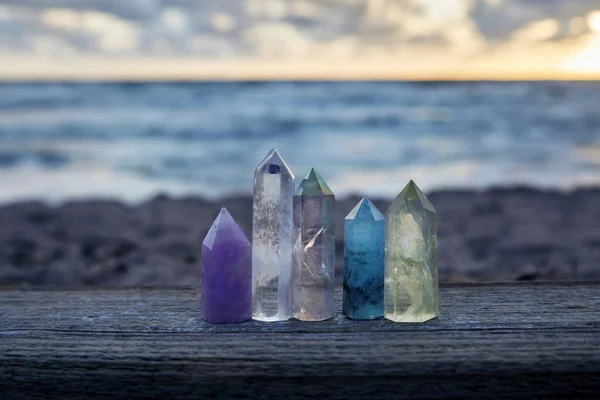 Heilende Reiki-Kristalle auf Holz mit Meer im Hintergrund bei Sonnenuntergang. Heilsteine am Meer. — Stockfoto