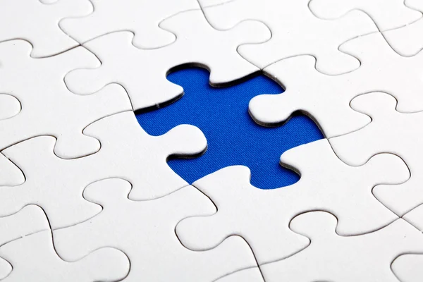 Zwykły biały puzzle układanki, na niebieskim tle — Zdjęcie stockowe