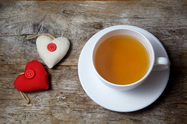 Corações de tecido e xícara de chá no fundo de madeira — Fotografia de Stock