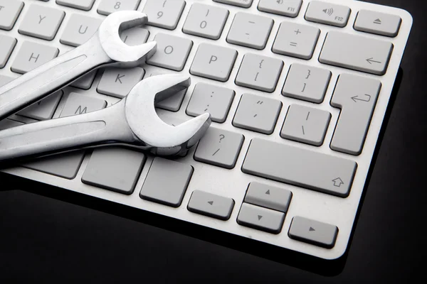 Spanners on computer keyboard — Stock Photo, Image