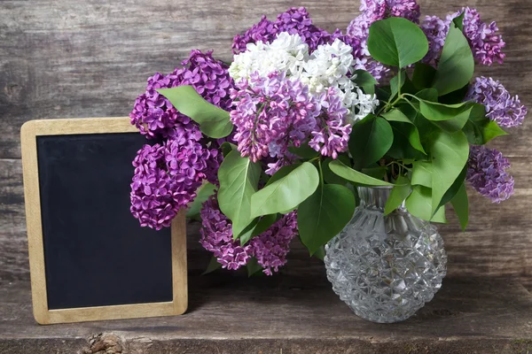 淡紫色的花的花瓶和黑板 — 图库照片