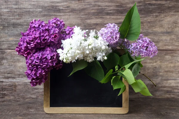 Lilac flowers in a vase and blackboard — Stock Photo, Image