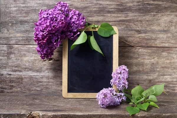 淡紫色的花的花瓶和黑板 — 图库照片