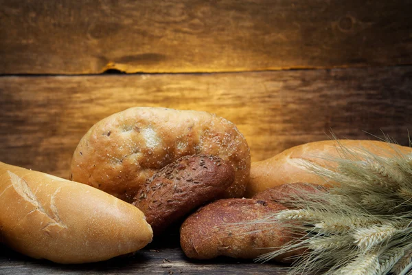 Pane fresco e grano sul legno — Foto Stock